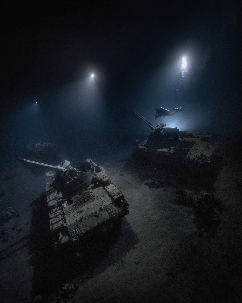 divers looking at submerged military tanks