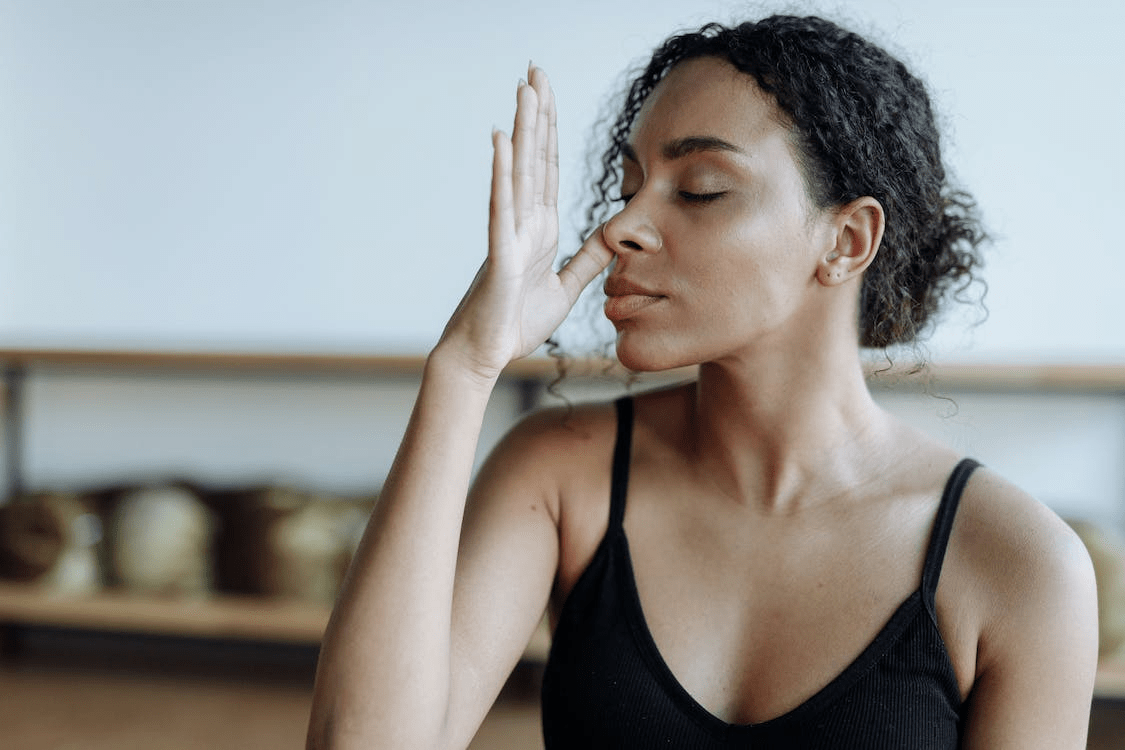 A woman in a black tank top is meditating